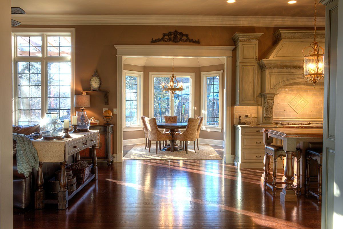 A living room and dining room in a house with hardwood floors and lots of windows.