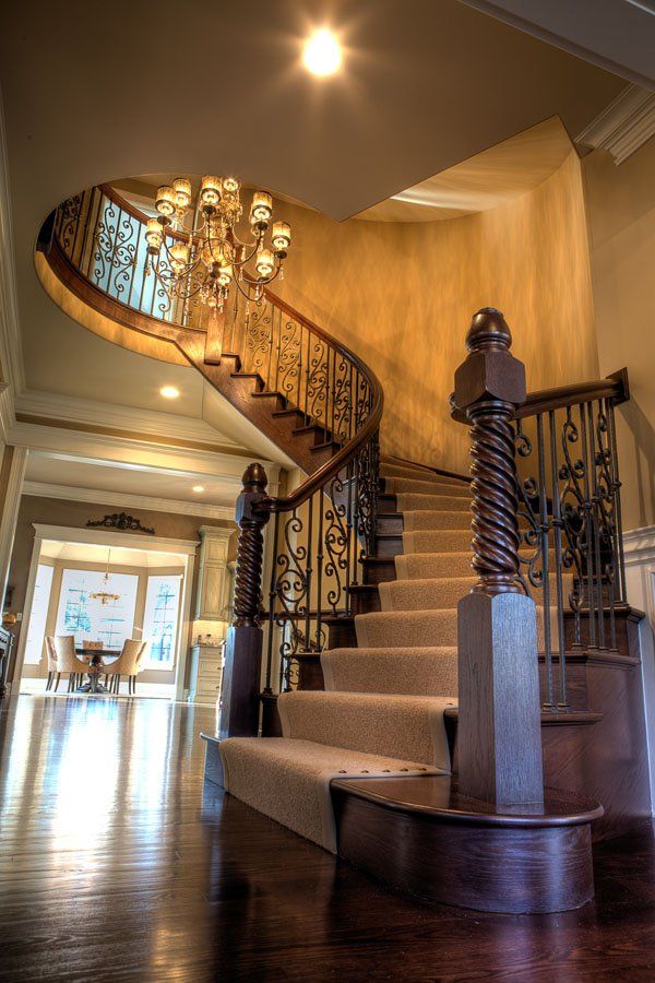 A curved staircase in a house with a chandelier