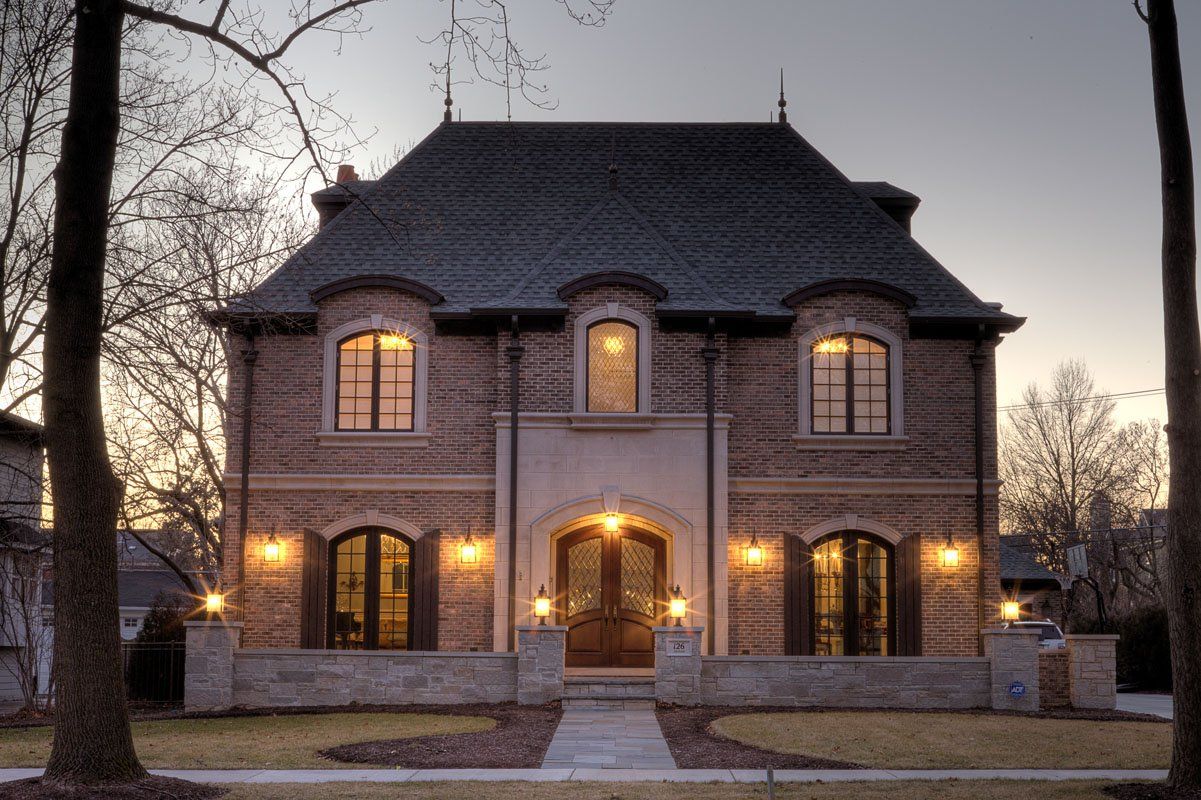 A large brick house with a black roof is lit up at night