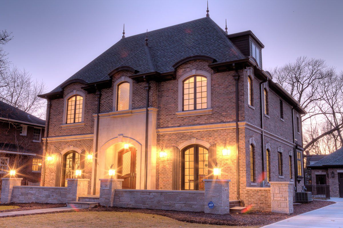 A large brick house with a black roof is lit up at night