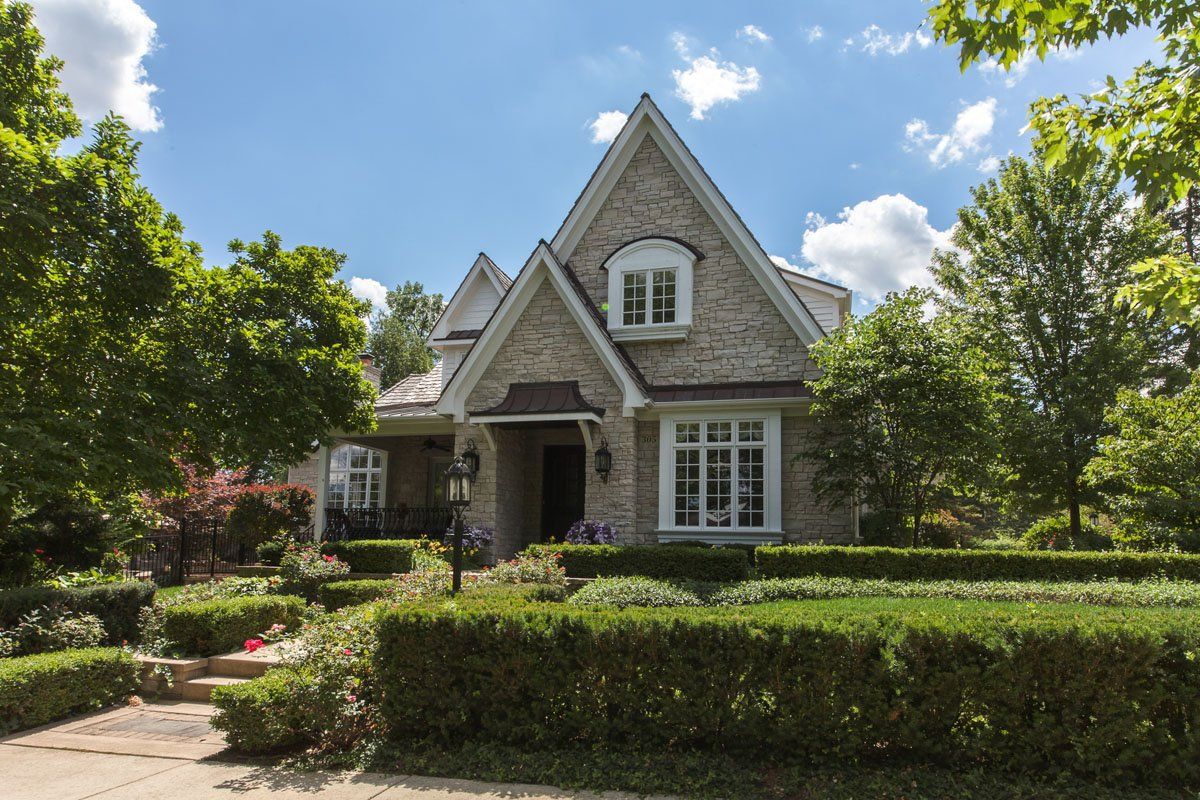 A large brick house surrounded by bushes and trees