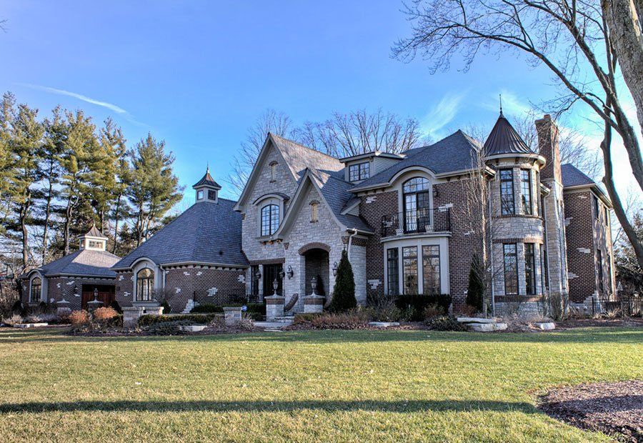 A large brick house is sitting on top of a lush green field.