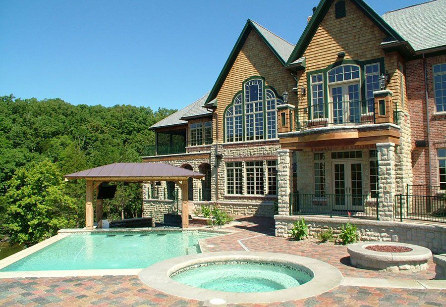 A large house with a swimming pool and hot tub in front of it