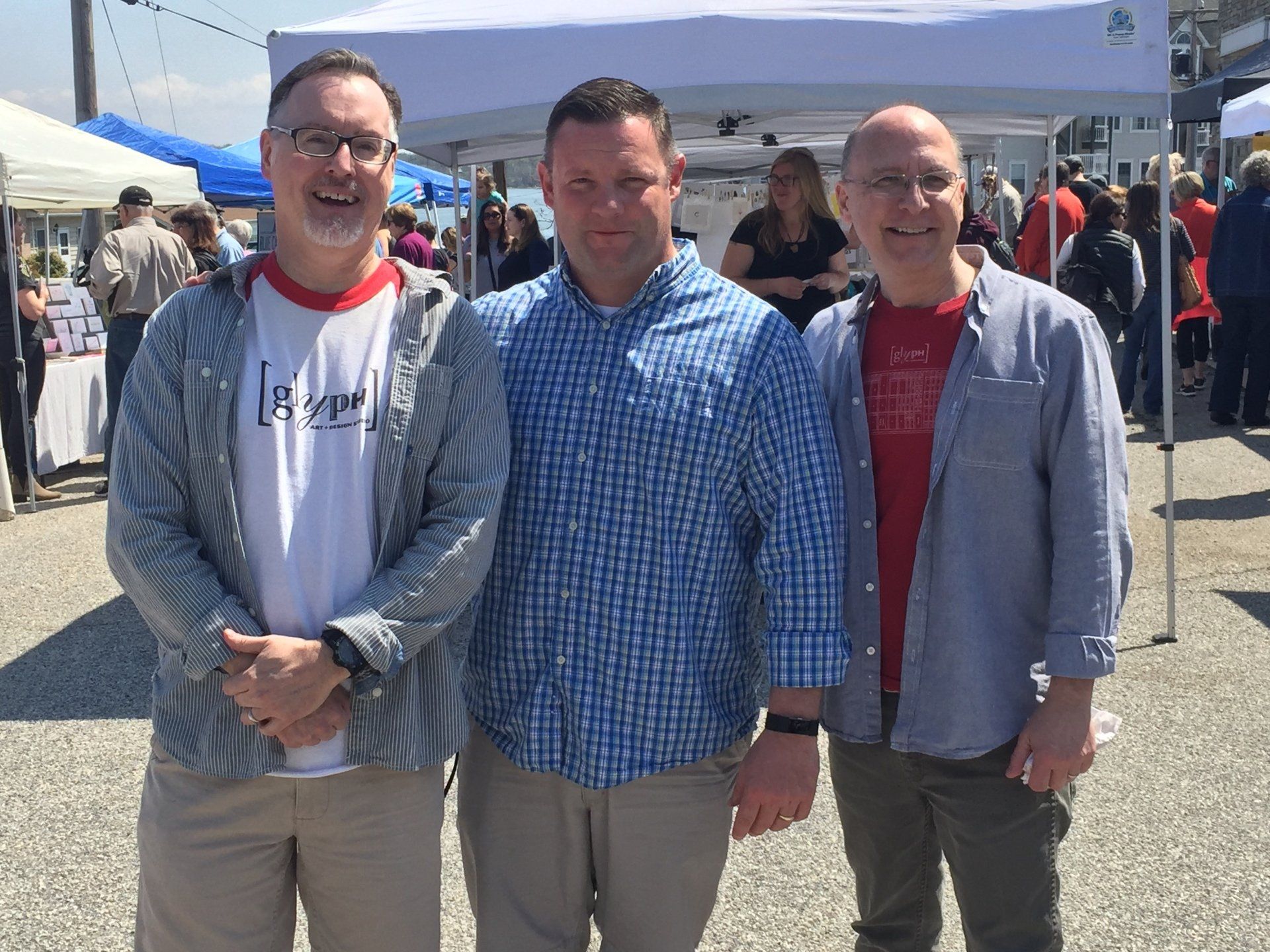 Three men are posing for a picture in front of a tent.