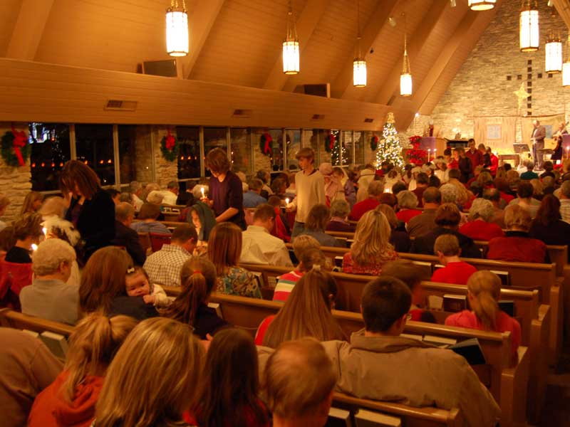 Church interior with people, candles, and a stage with musicians.