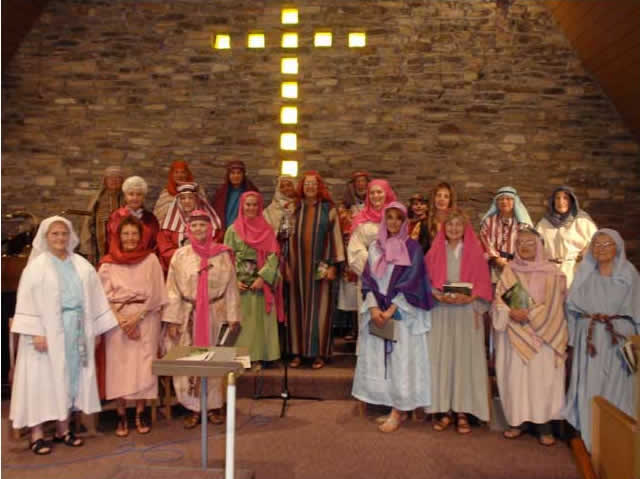 People in biblical costumes posing in front of a cross in a church.