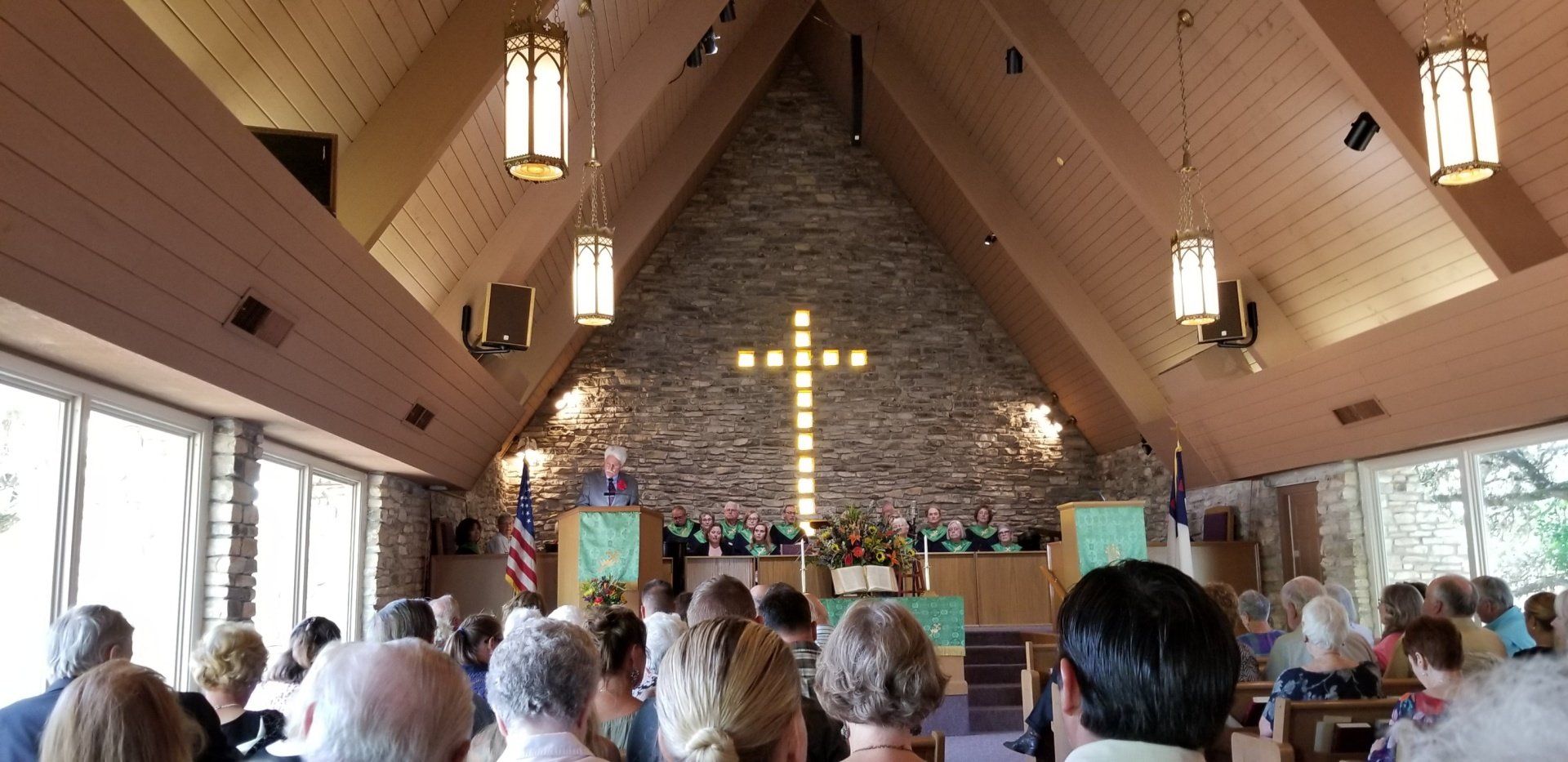 A church interior with a cross on the back wall and people attending a service.