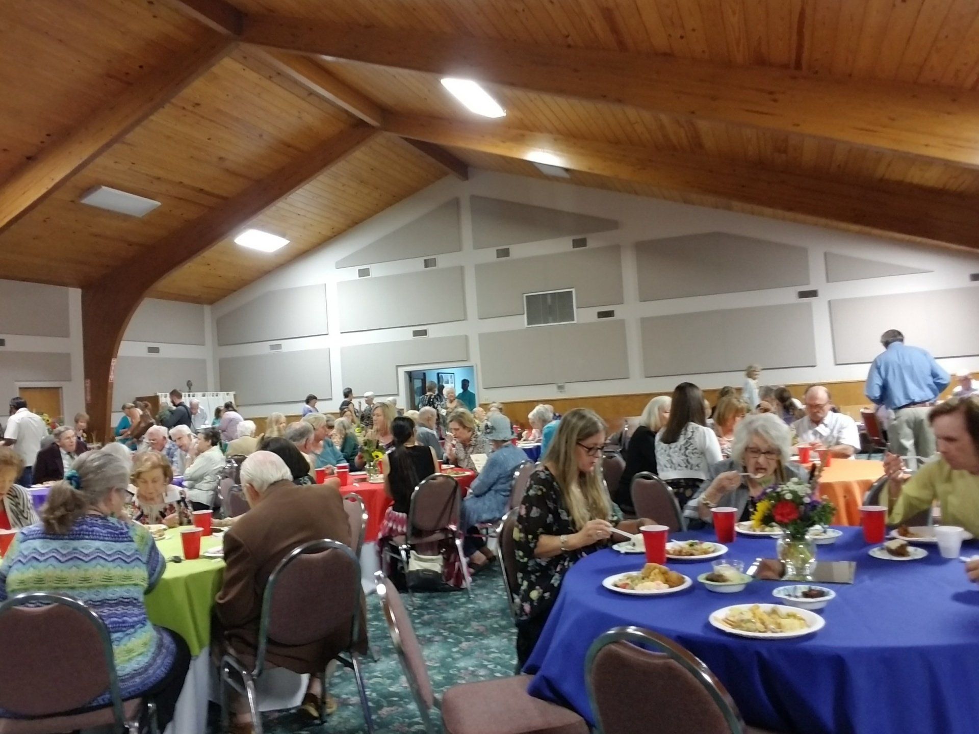 Large room with people seated at tables, likely a gathering or event.