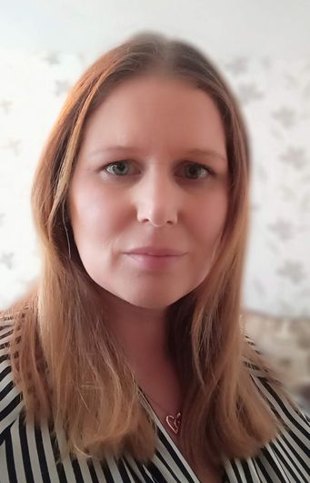 A woman with long hair is wearing a striped shirt and a necklace.