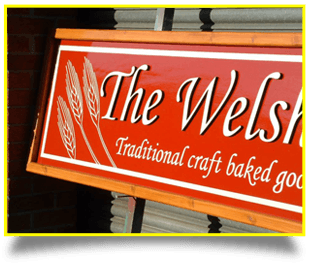 A red sign with italic white writing for a shop selling baked goods