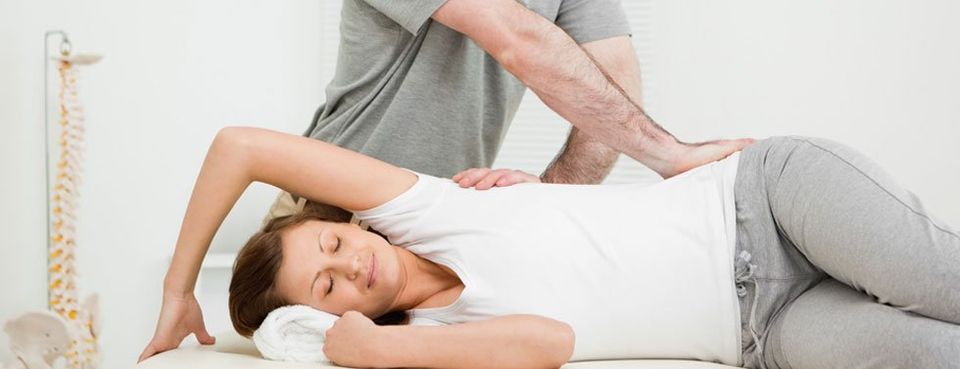 Chirporactor crossing his arms while massaging a woman in his medical office