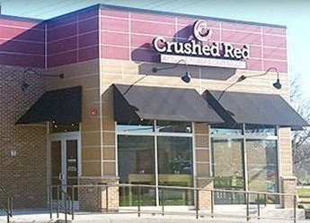 The front of a crushed red restaurant with black awnings.