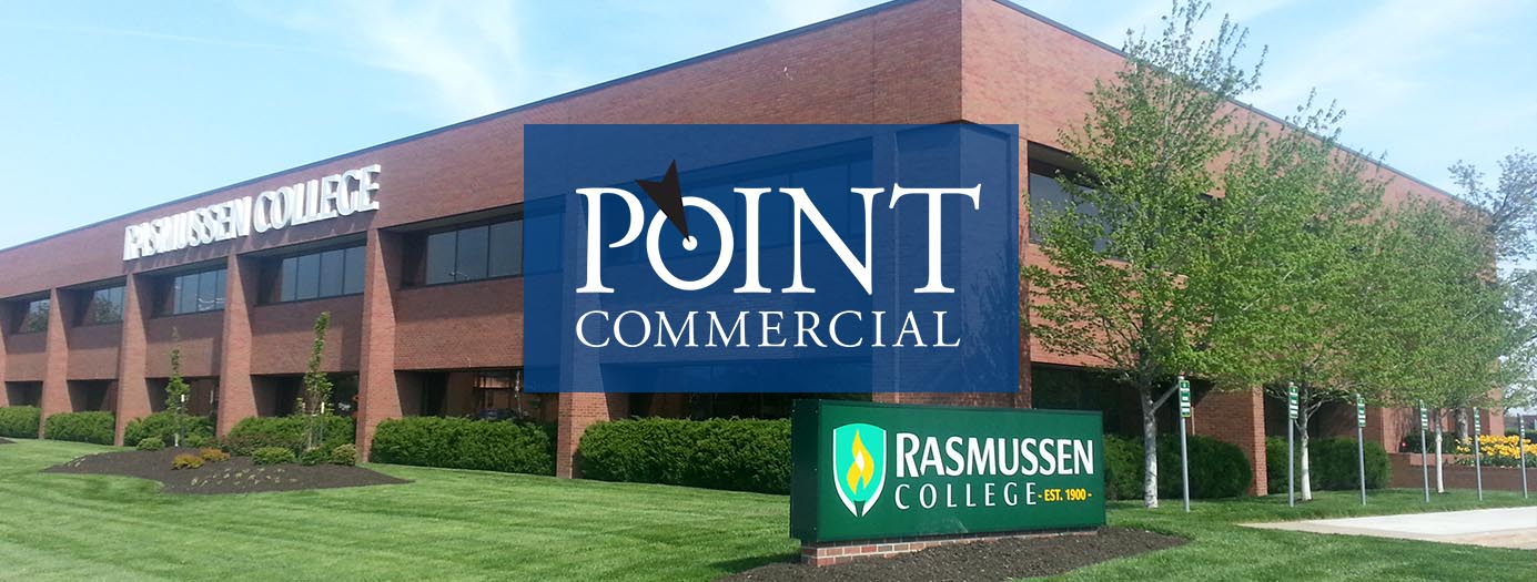A large brick building with a point commercial sign in front of it