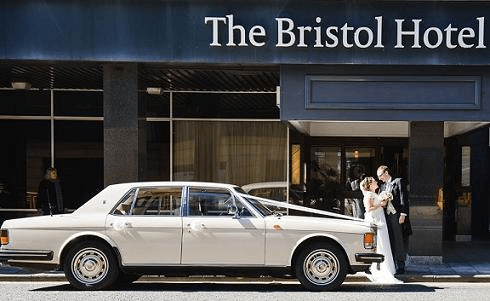 Spirit Wedding Cars | A white car is parked in front of the bristol hotel
