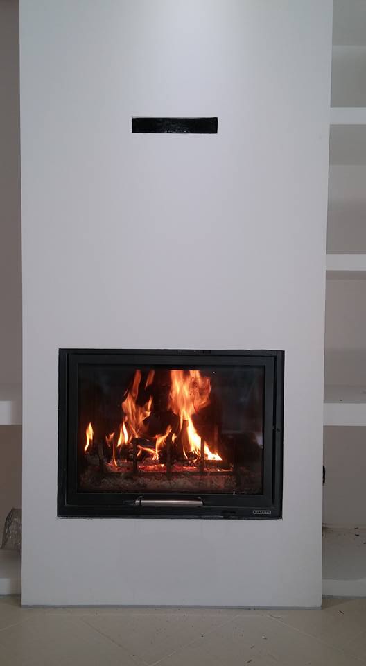 Caminetto moderno bianco con fiamma in vetro incorniciata di nero, in una stanza minimalista.