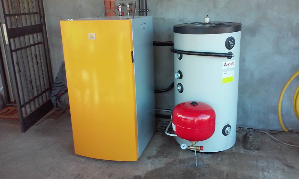 Elettrodomestico giallo e scaldabagno bianco con serbatoio rosso in un locale simile a un garage.