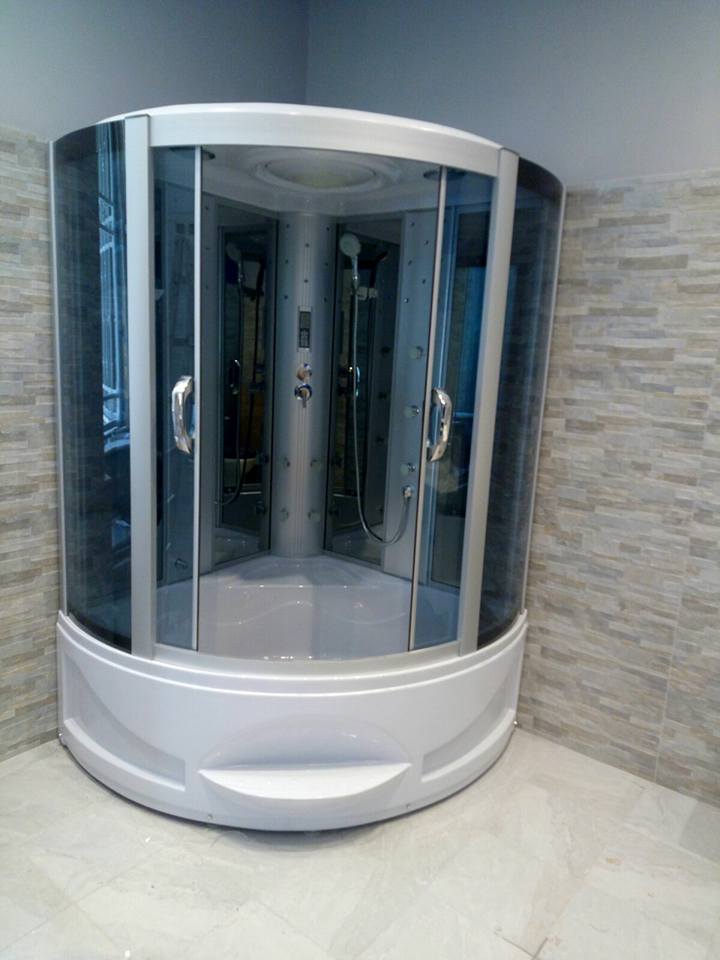 Cabina doccia bianca curva con ante in vetro in un bagno piastrellato