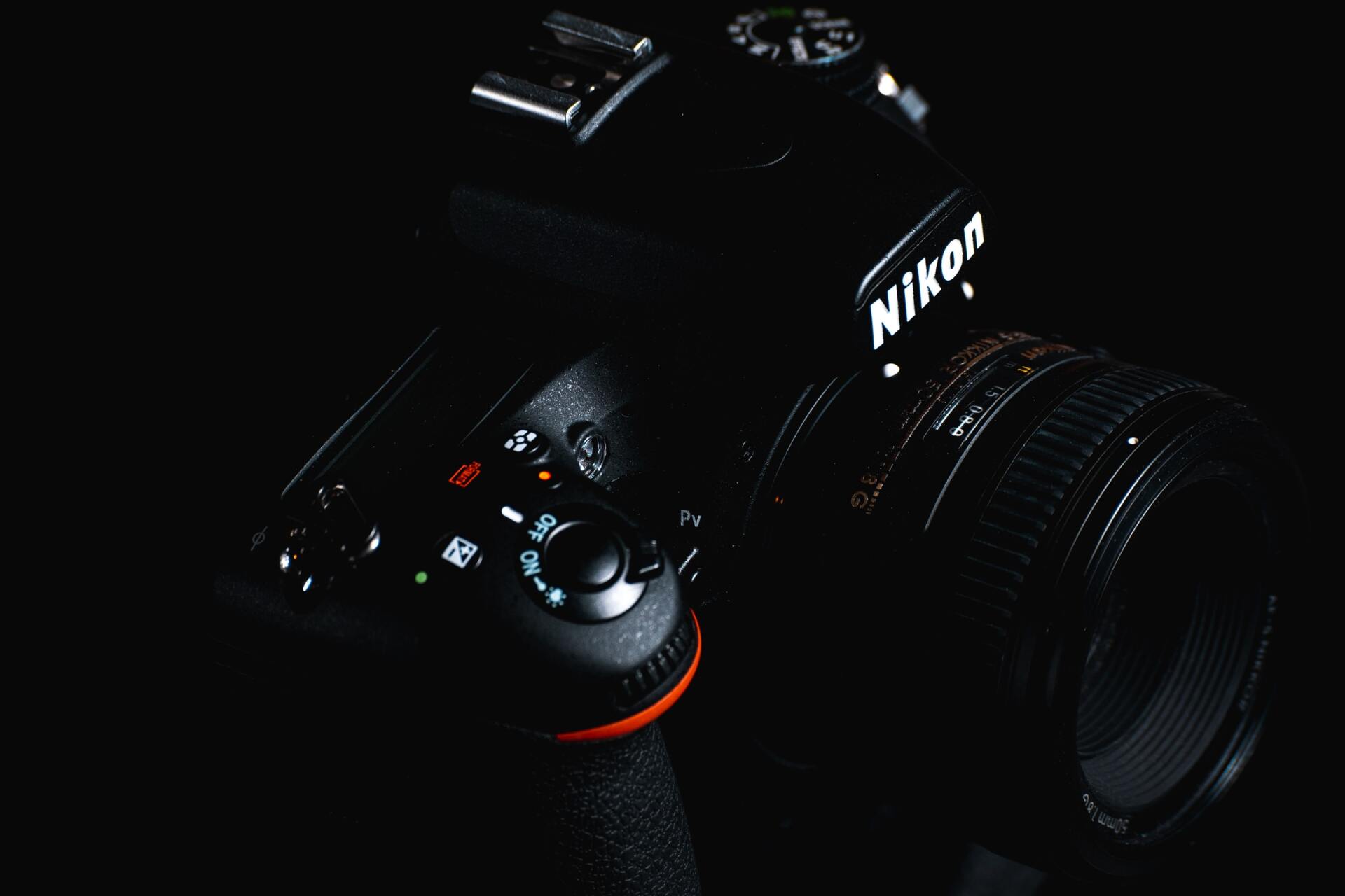 a black nikon camera is sitting on a black surface .