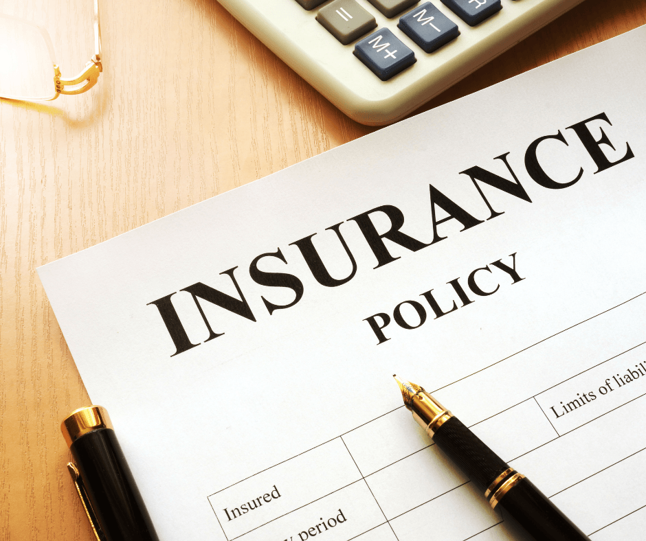 Insurance policy document on a desk with a calculator and pen
