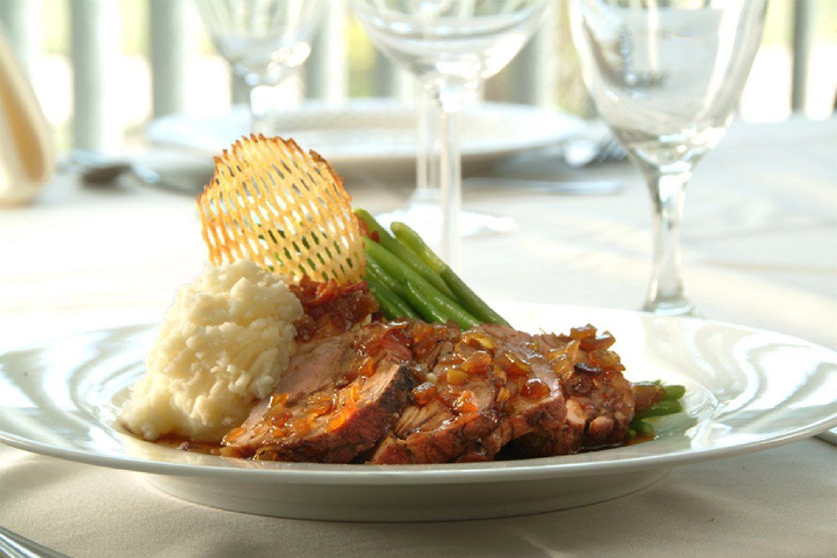A white plate topped with meat , mashed potatoes and green beans on a table.