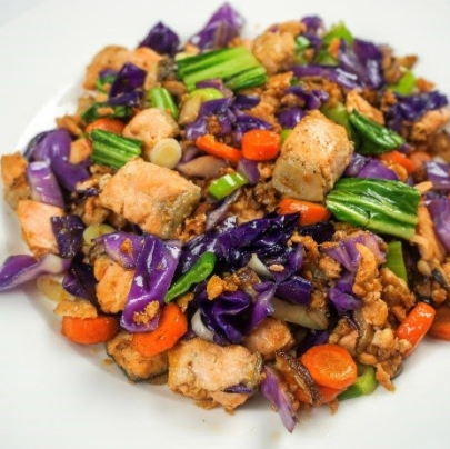 Chicken and vegetable stir-fry with red cabbage, carrots, and green onions on a white plate.