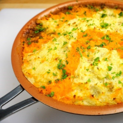 Shepherd's pie in copper-colored pan, topped with mashed potatoes and parsley.