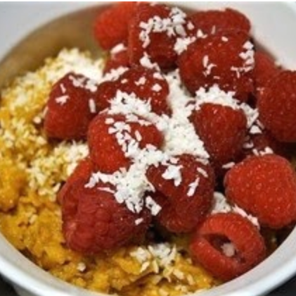 Oatmeal topped with red raspberries and shredded coconut in a white bowl.