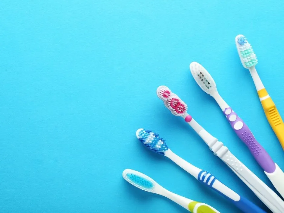 Five colorful toothbrushes on a blue background.