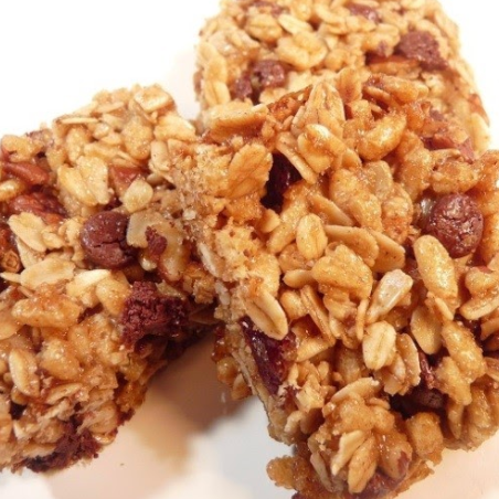 Granola bars, close-up, stacked. Showing oats, chocolate chips, and nuts in a golden-brown hue.