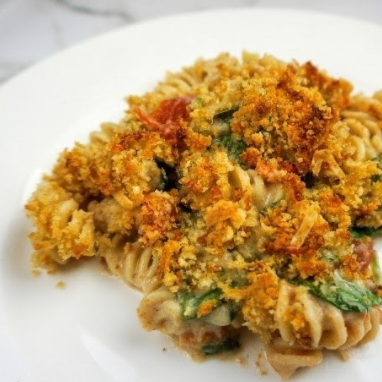 Pasta casserole with crispy breadcrumb topping on white plate.