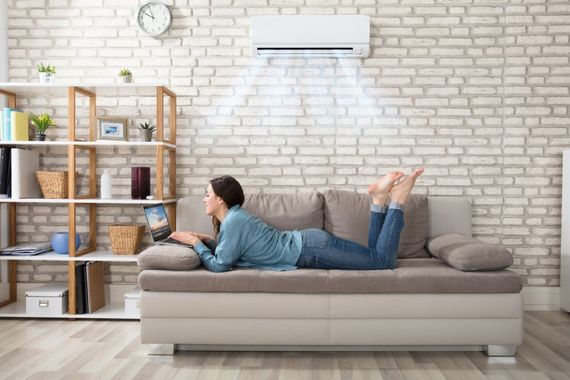 ragazza lavora al PC godendosi l'aria che esce dal condizionatore