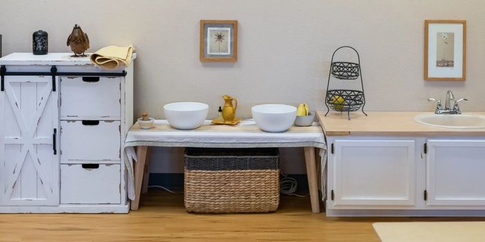 A montessori classromm with a wooden toy kitchen with two sinks and a dresser.