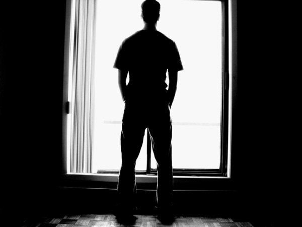 A silhouette of a man standing in front of a window.