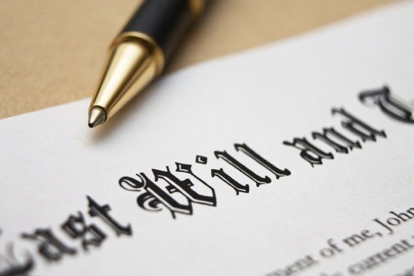 A pen rests on top of a last will and testament