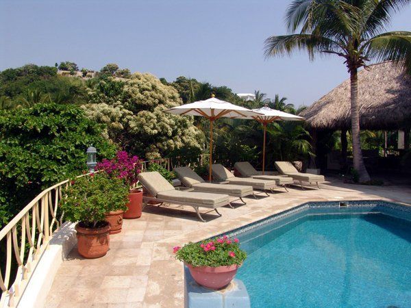 a large swimming pool surrounded by chairs and umbrellas