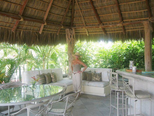 a woman in a hat is standing under a thatched roof