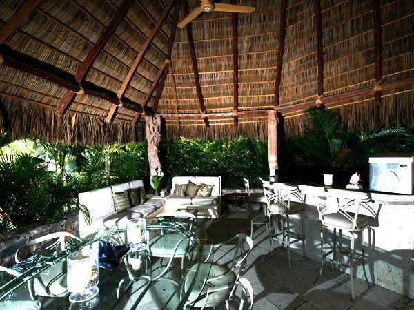 a gazebo with a thatched roof and a ceiling fan