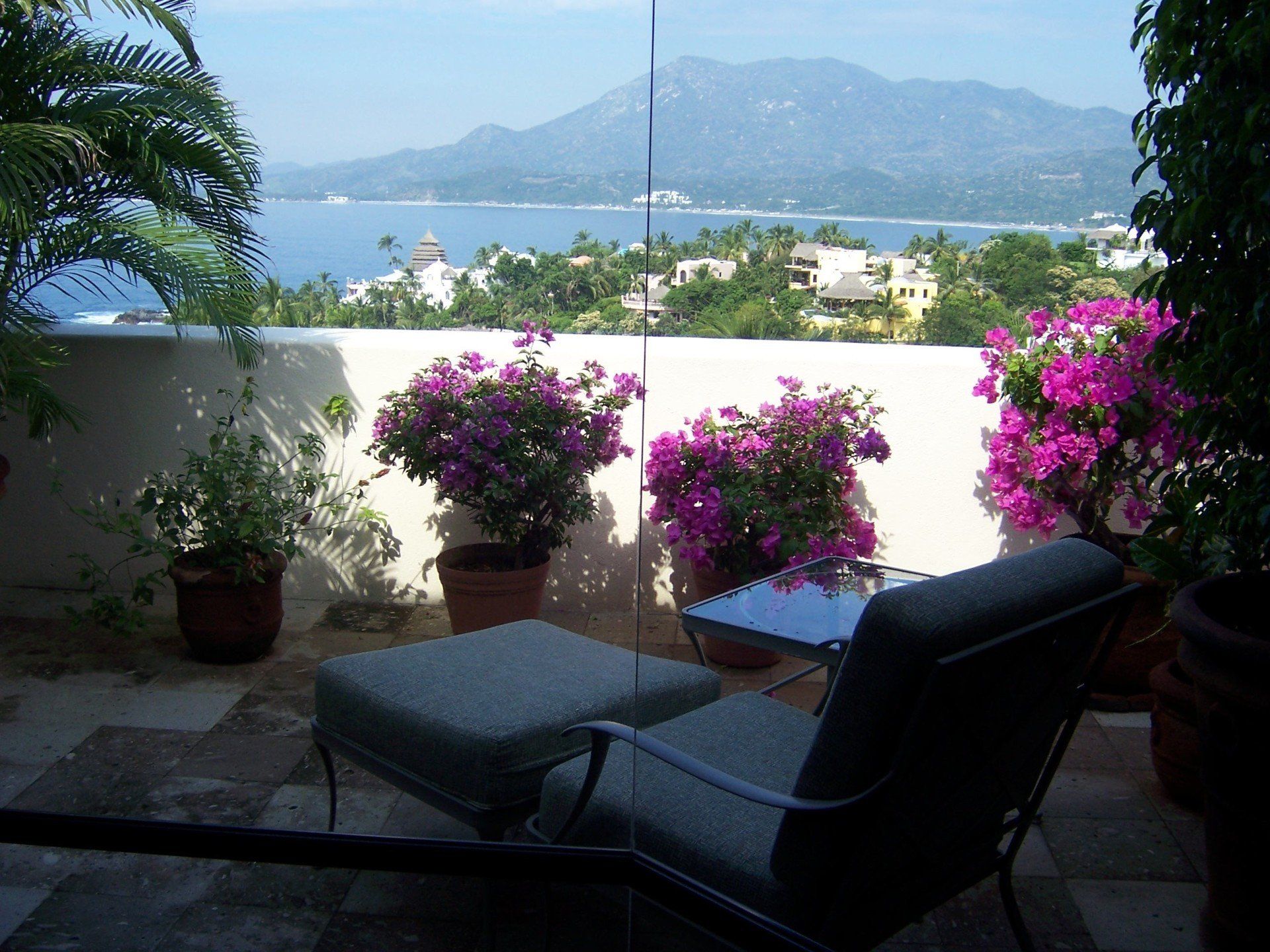a balcony with purple flowers and mountains in the background