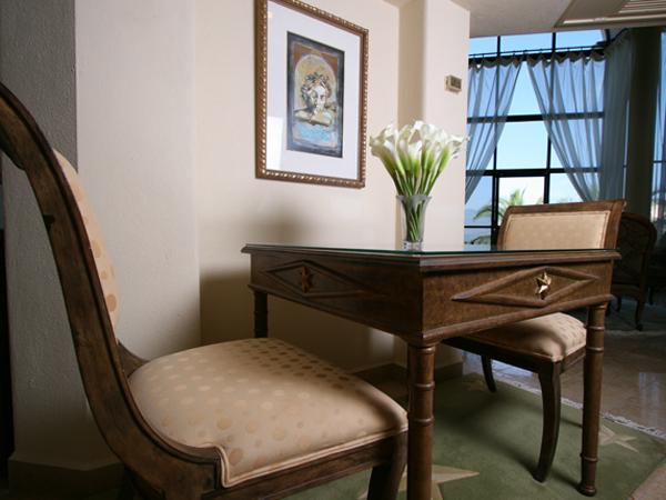 A chair sits next to a table with a vase of flowers on it