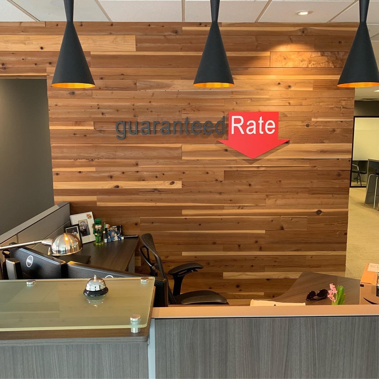 Reception desk with wooden wall, black pendant lights, and a red “Rate” sign above the counter
