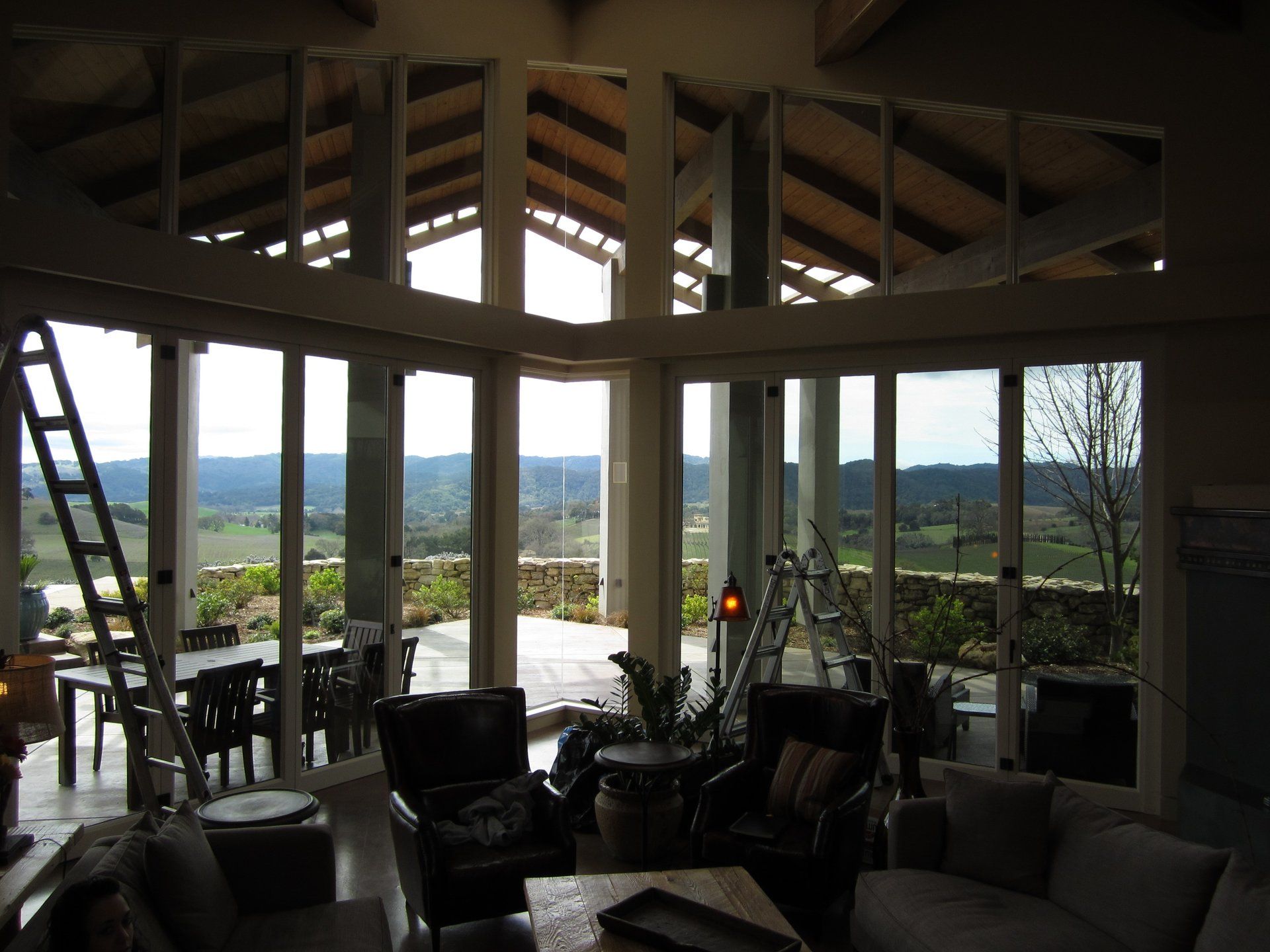 Panoramic living room with large windows overlooking a distant landscape at dusk