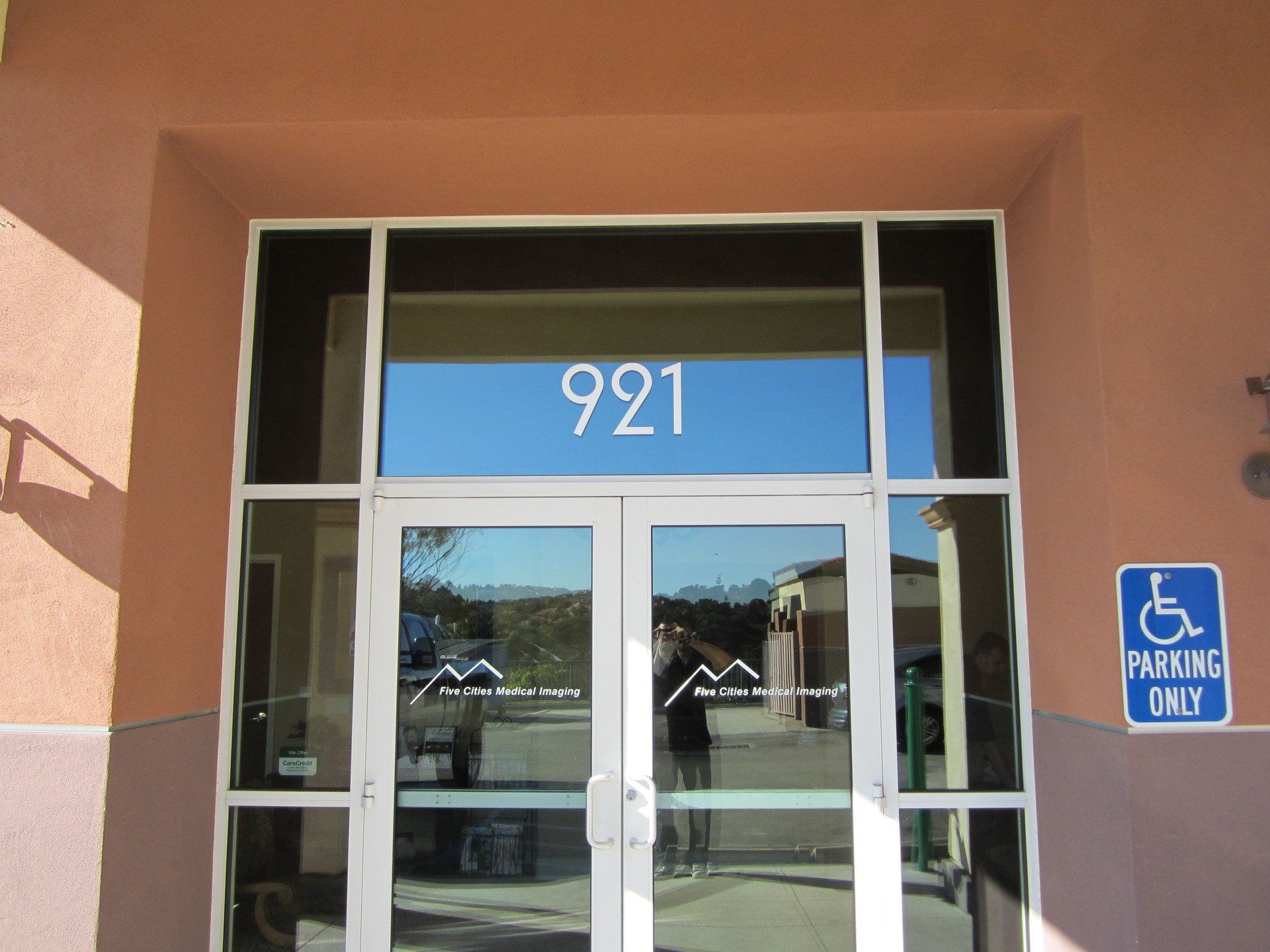 Glass entrance with number 921 and a blue accessible parking sign beside the door