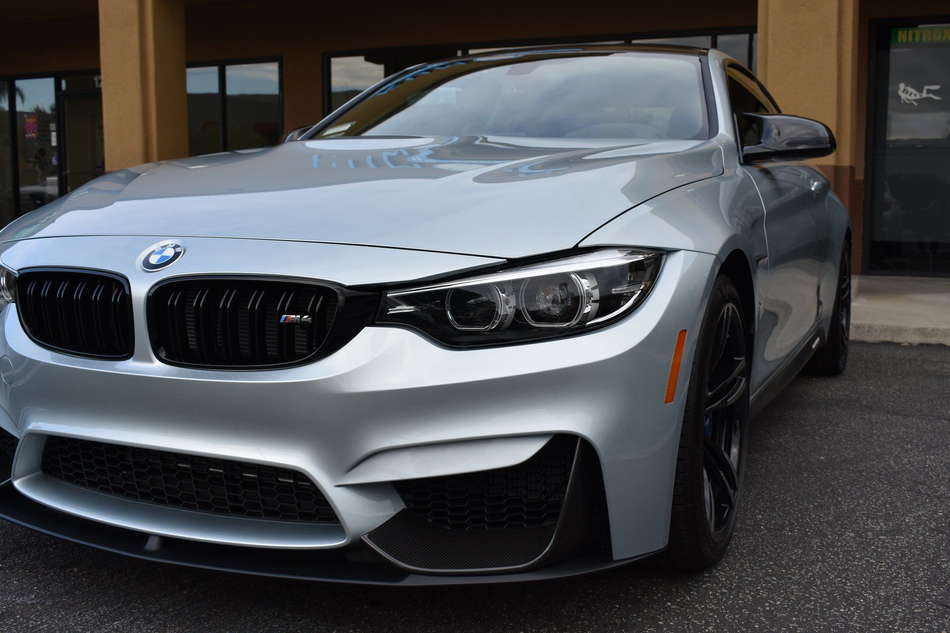 Silver BMW sports coupe parked outside a building, front view.