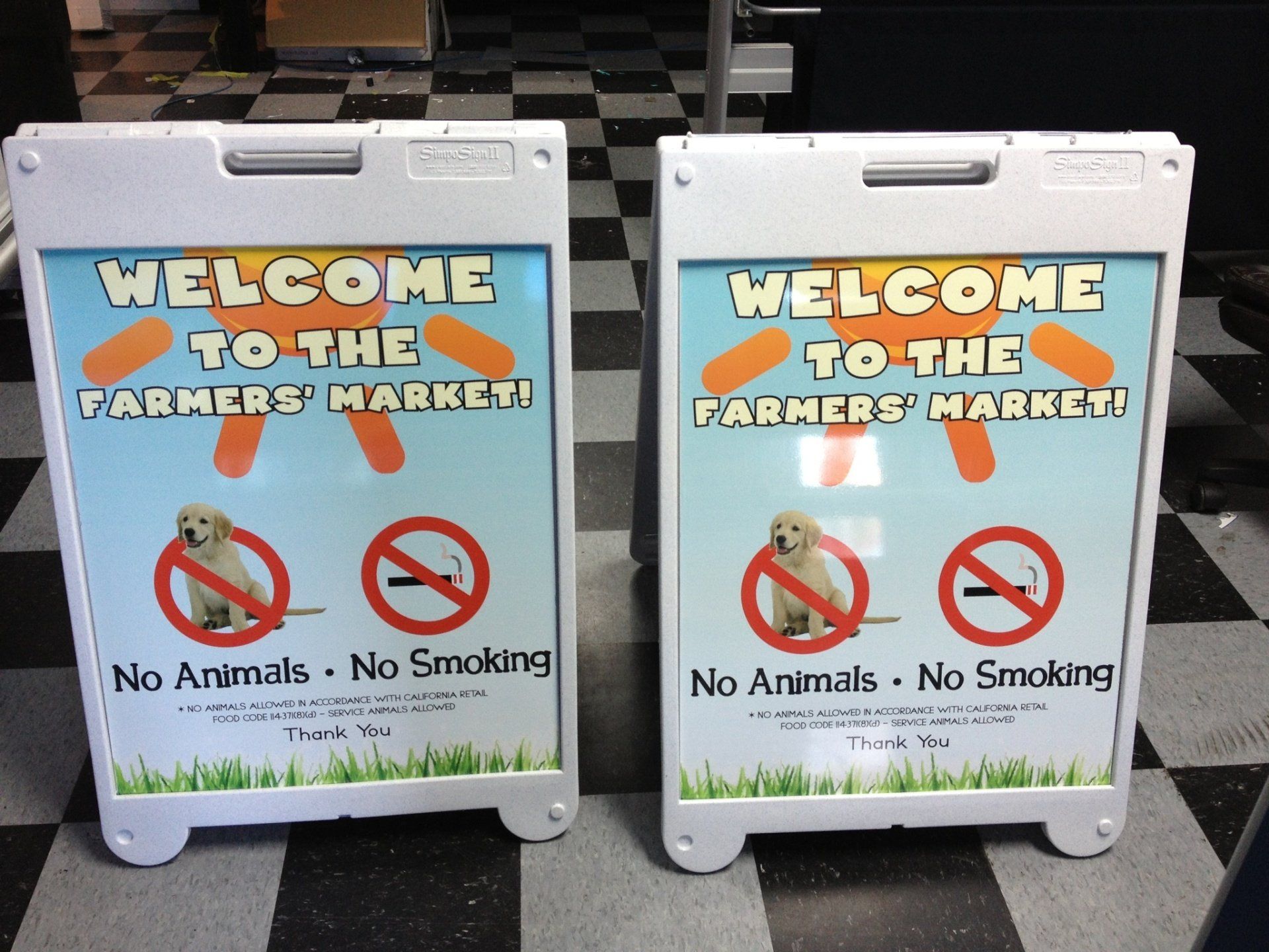 Two white signboards reading “Welcome to the Farmers Market,” with no animals and no smoking symbols.