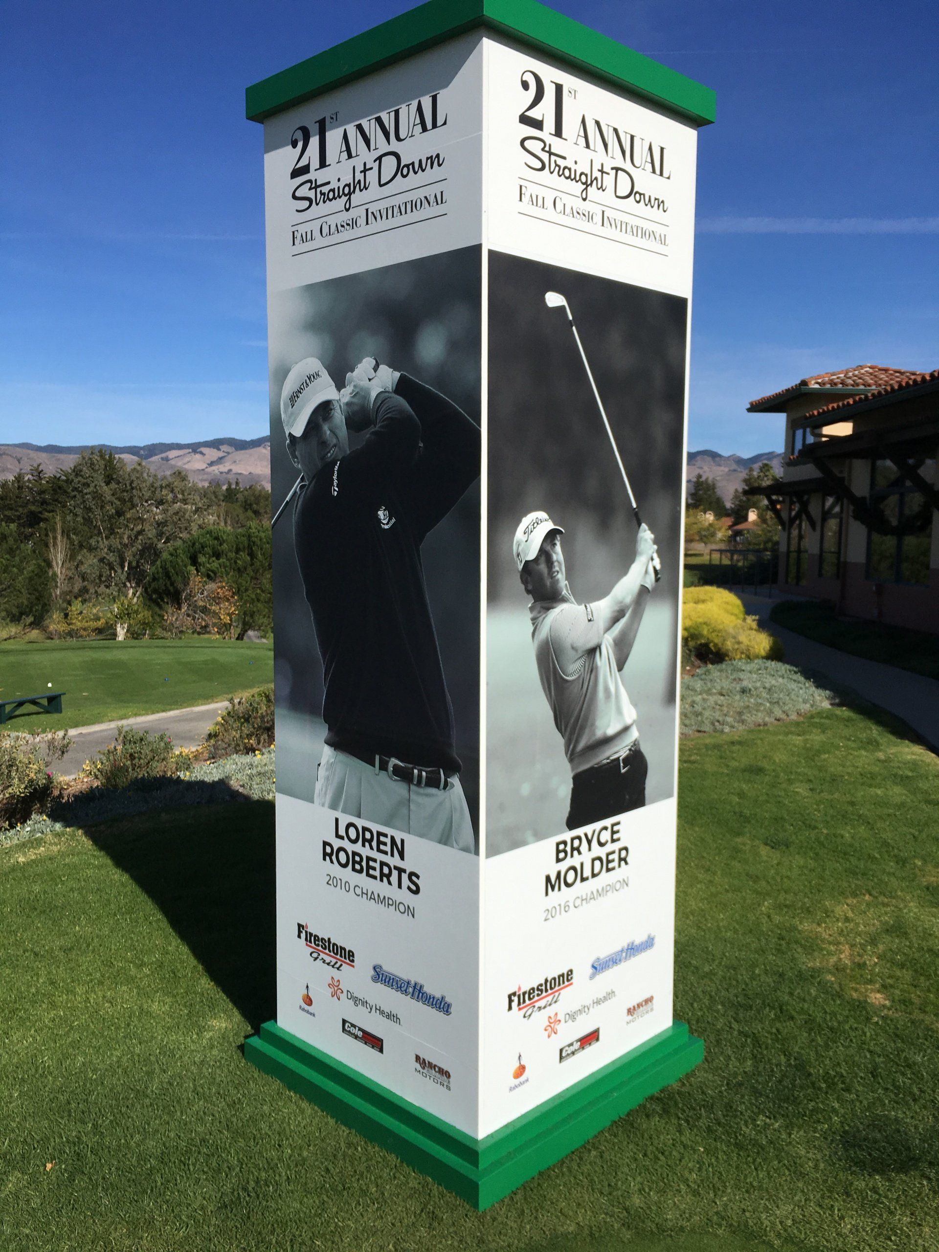 Tall outdoor exhibition pillar with black-and-white golf photos and text, set in a grassy landscape.