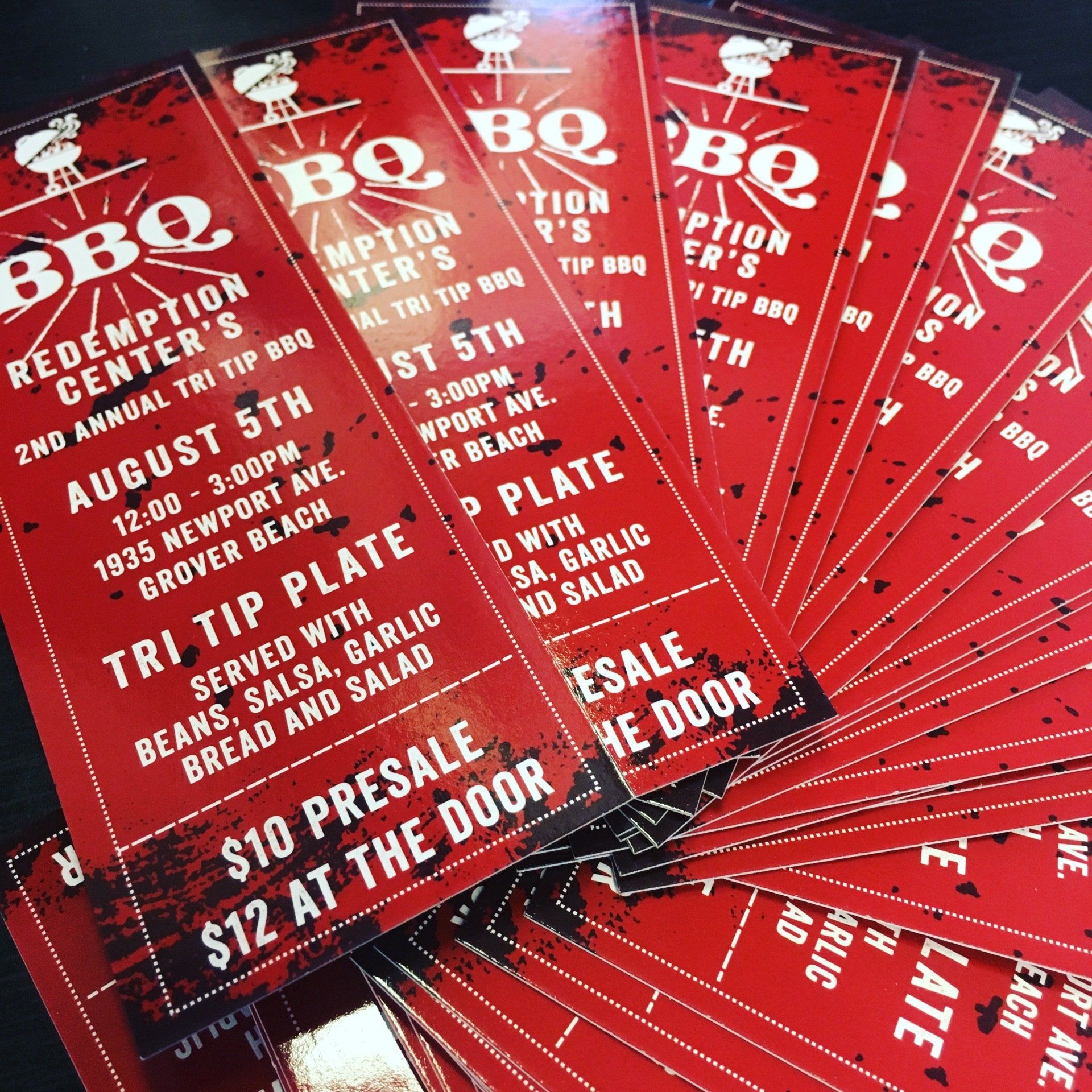 Stack of red barbecue event flyers with white text, fanned out on a table.