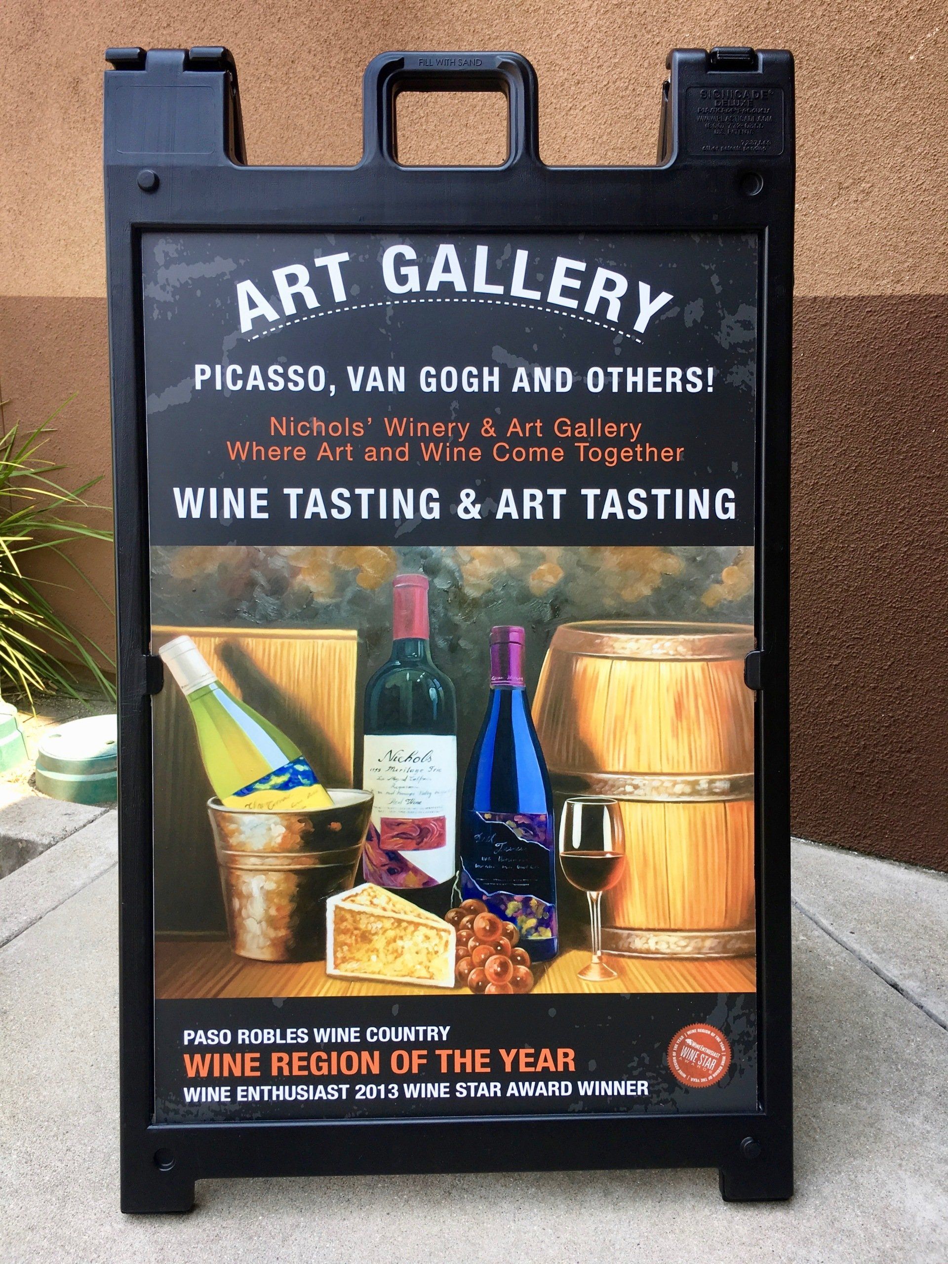 Sidewalk sign for an art gallery wine tasting and art tasting event with wine bottles and glasses.