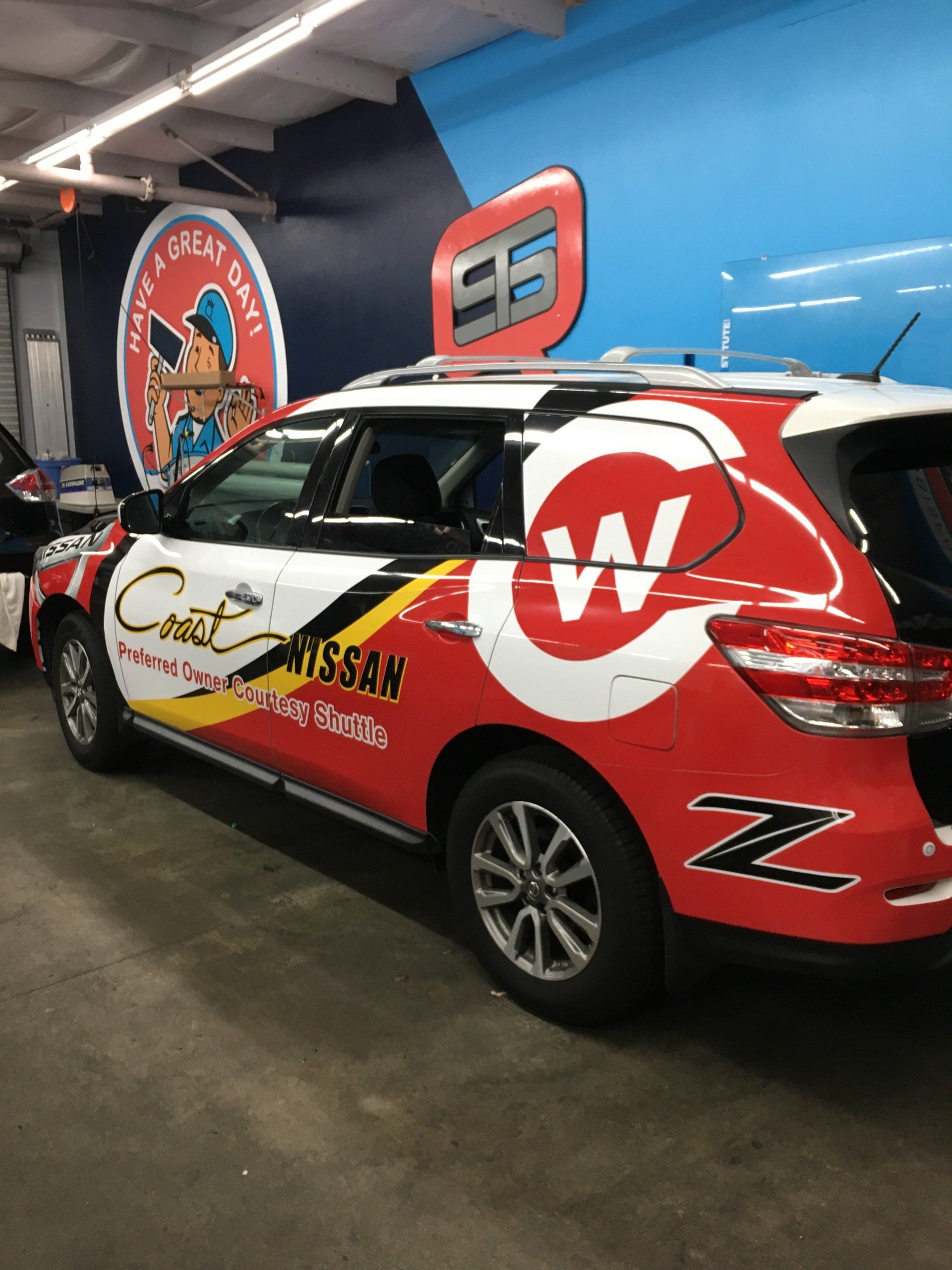 Red-and-black branded SUV in a garage, covered in racing-style decals and a large white “W” logo.