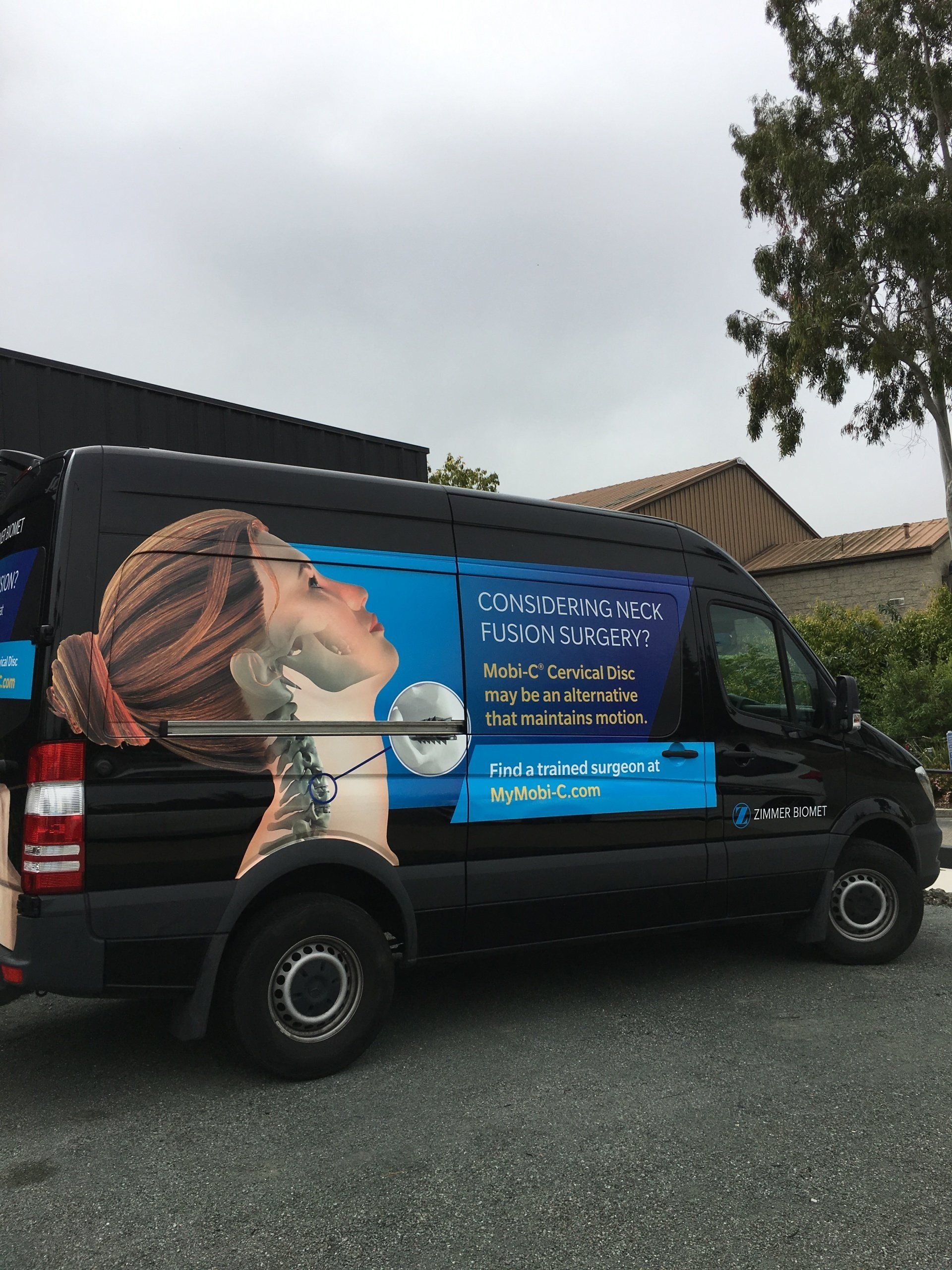 Black van with a large advertisement showing a person drinking from a water bottle and white text on the side.