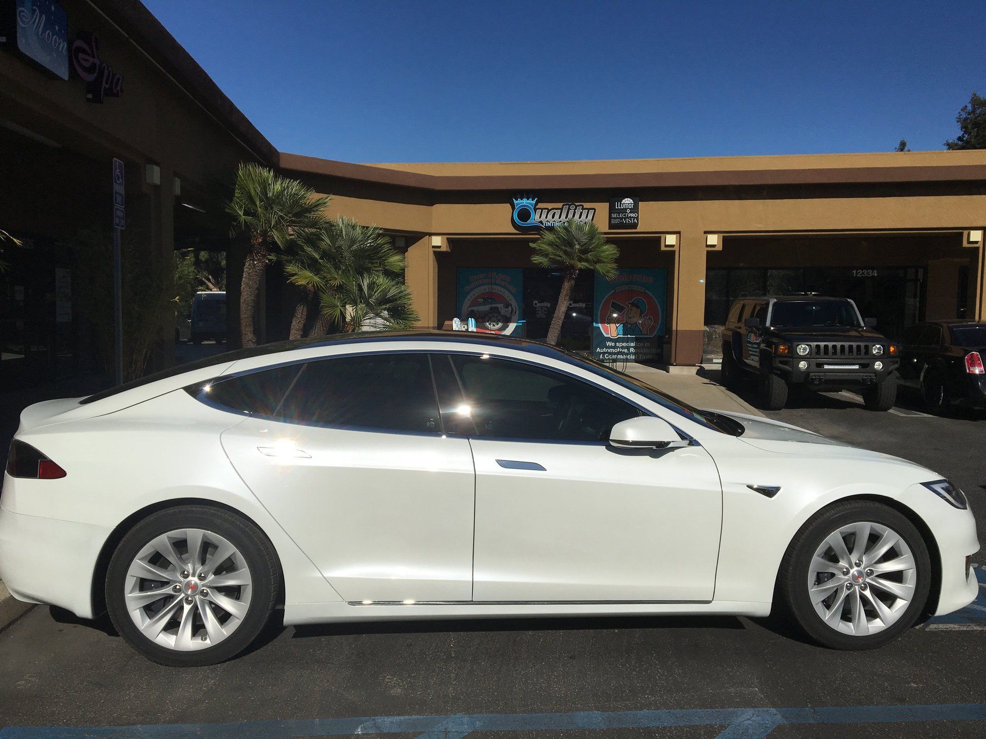 White sedan parked outside a storefront in a parking lot
